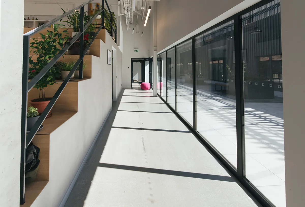Corridor with glass windows and a doorway at the end of an office interior