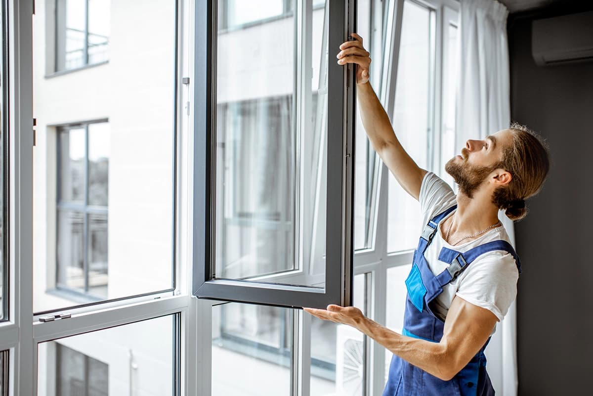 Workman adjusting plastic window frames at home